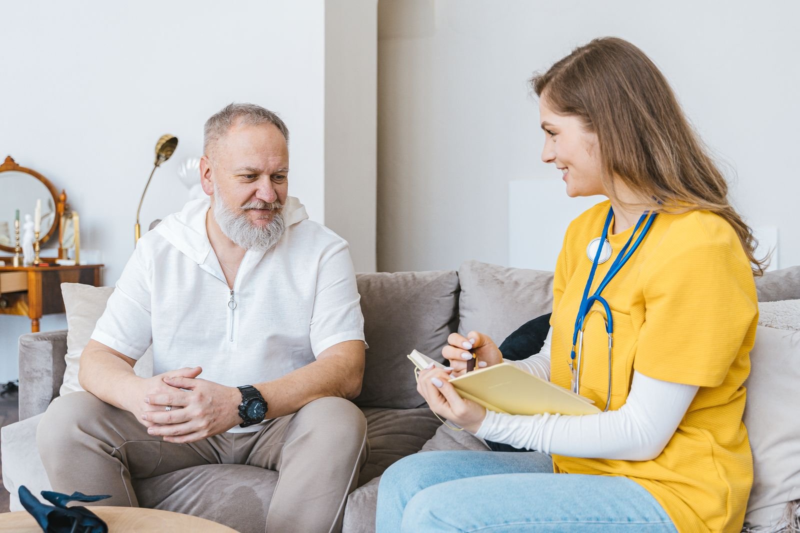 A clinician consulting warmly with a patient in his living room